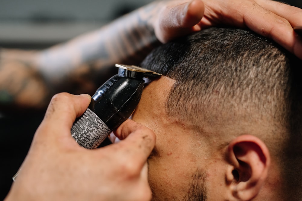 Close-up of a barber using an electric razor to trim a man's hairline