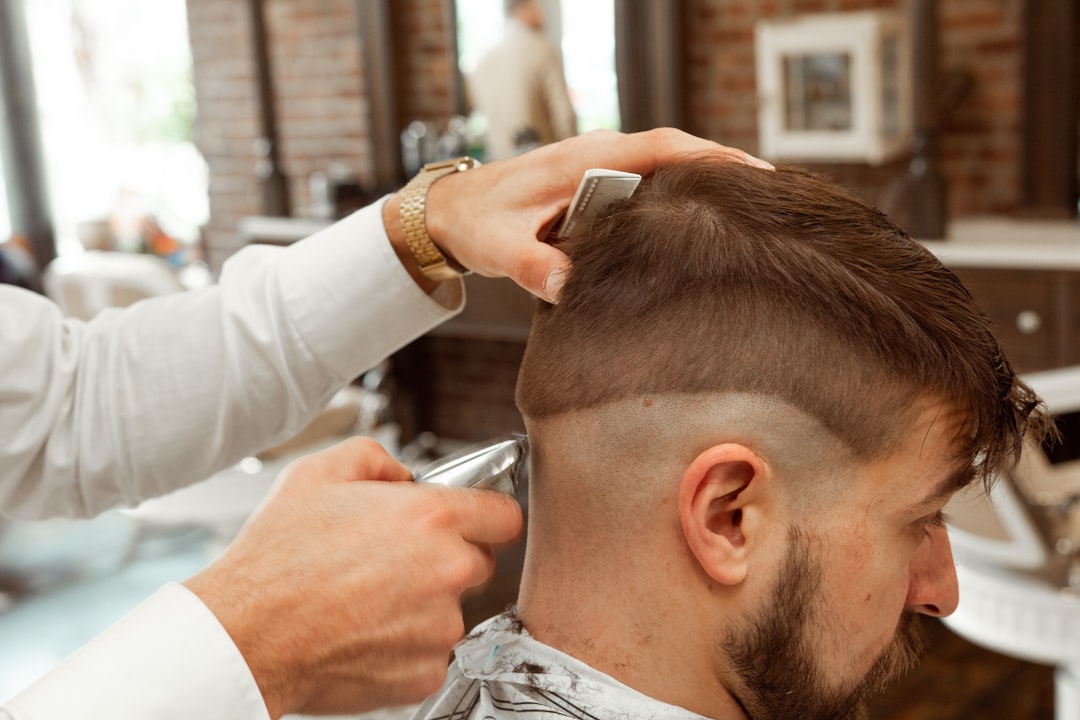 A barber cuts a man's hair with clippers and a comb in a barbershop