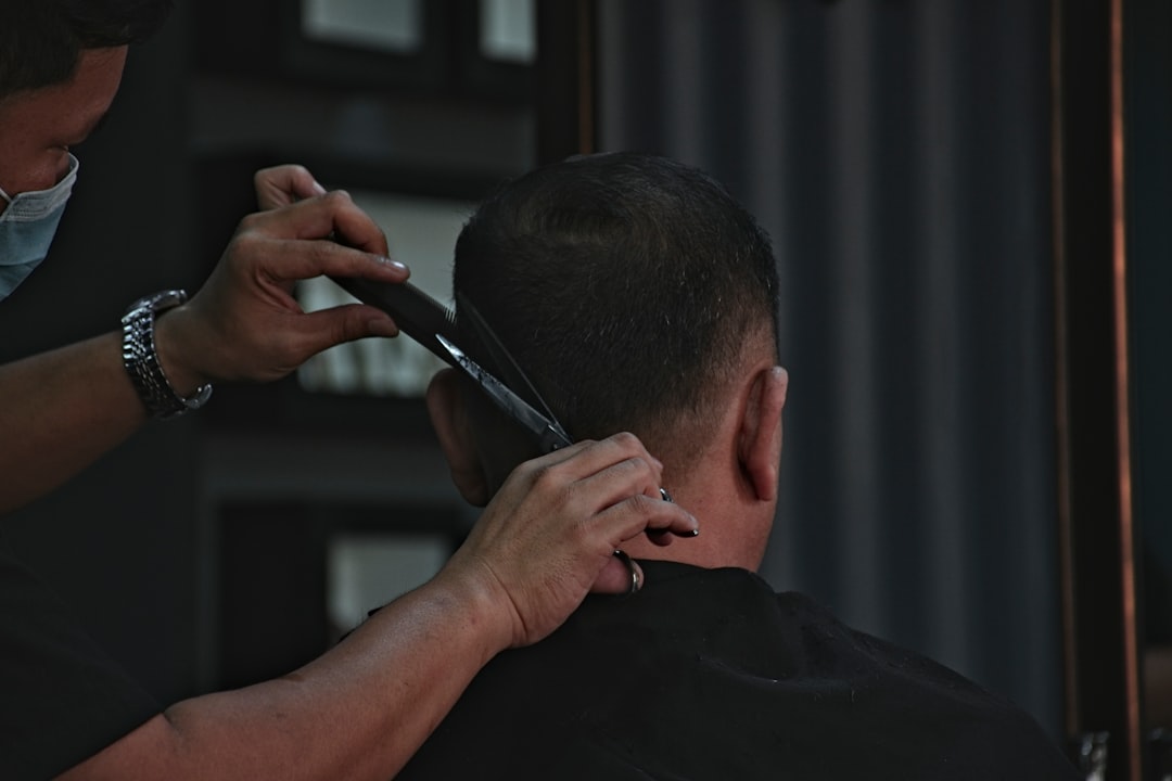 A barber cuts a man's hair with scissors and a comb