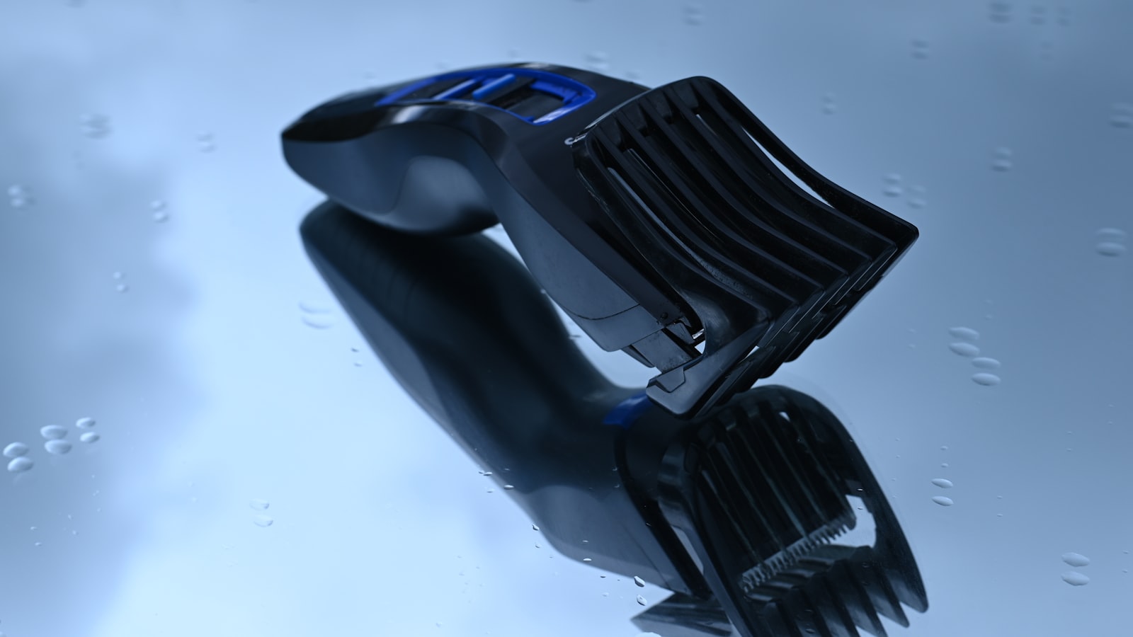 A black and blue electric shaver on a wet, reflective surface