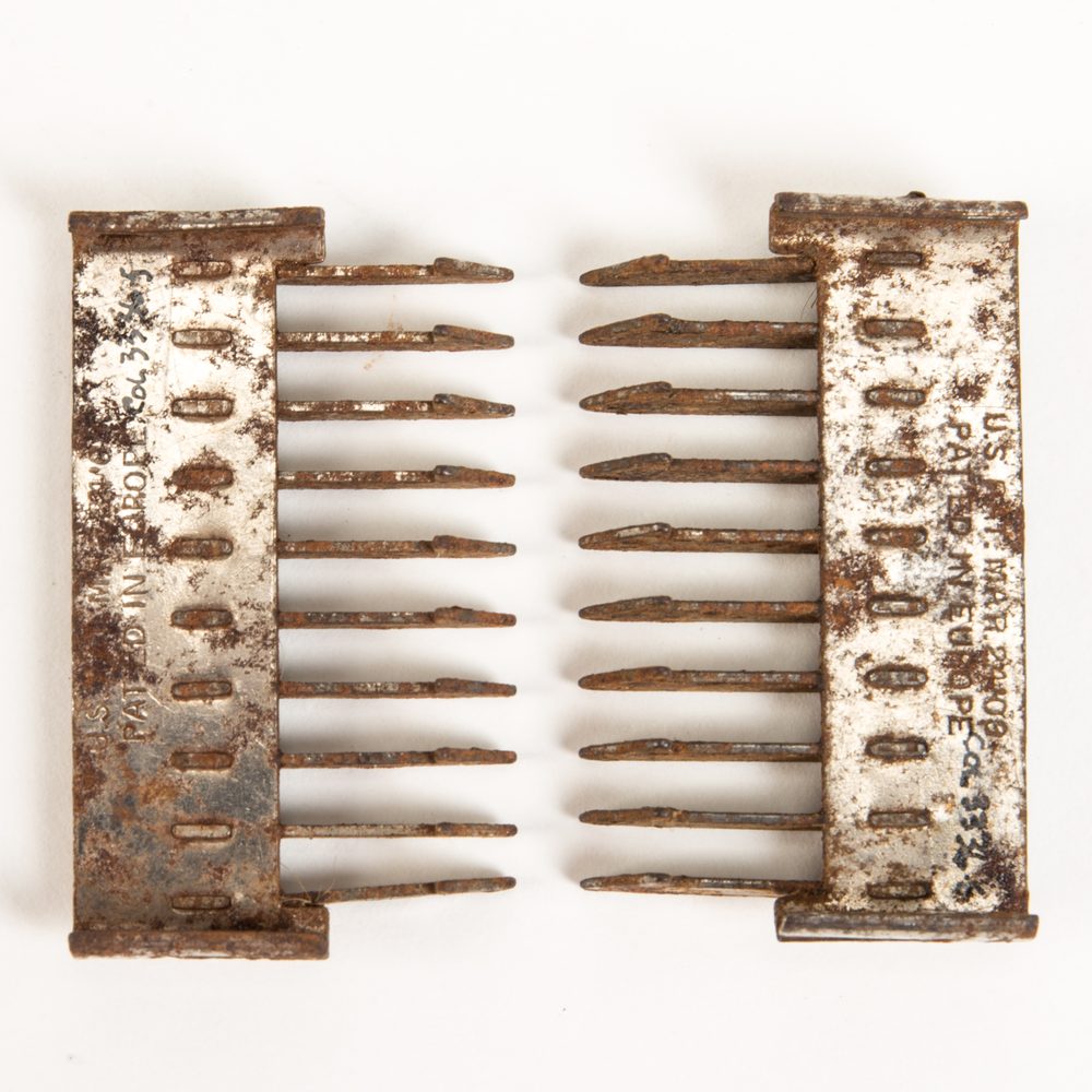 Two rusty metal comb-like fastener pieces facing each other on a white background